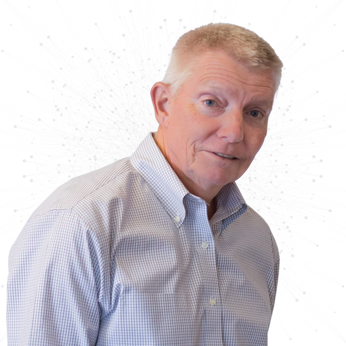 A middle-aged man with short light hair wearing a light checkered button-up shirt stands in front of a white background with faint dot and line patterns.