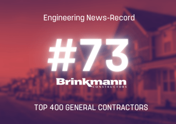 Graphic with blurred houses in the background reads Engineering News-Record #73 Brinkmann Constructors Top 400 General Contractors.