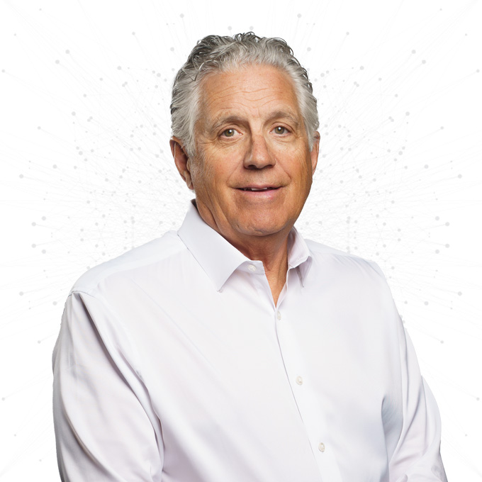 A middle-aged man with gray hair wearing a white button-up shirt, smiling slightly, poses against a white background with faint abstract dotted lines.