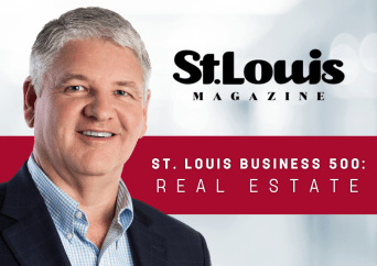 A smiling man in a suit stands in front of a blurred background. The image features St. Louis Magazine and ST. LOUIS BUSINESS 500: REAL ESTATE text over a red banner.