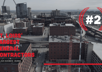 Aerial view of downtown St. Louis with construction sites and buildings. Text reads St. Louis Largest General Contractors and a large #2 with a red laurel wreath graphic. The Gateway Arch is visible in the background.
